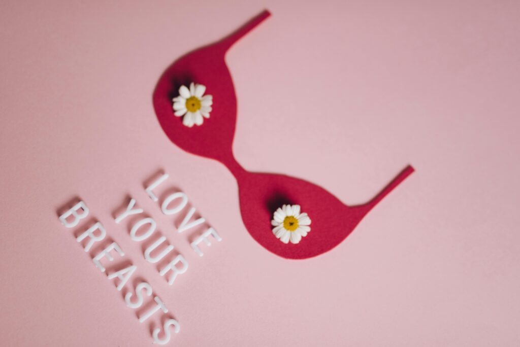 Pink background with bra shape and daisies promoting self-care for breast health.